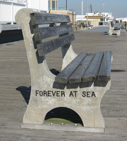 a bench on the boardwalk with an inscription - forever at sea